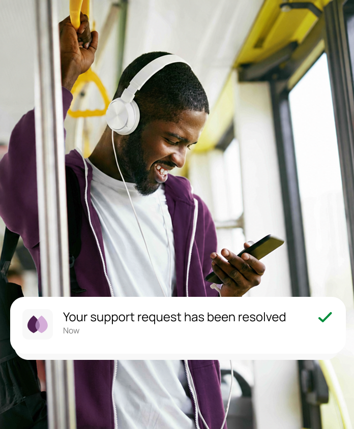 A man on a bus smiling at his phone; a notification reads “Your support request has been resolved”